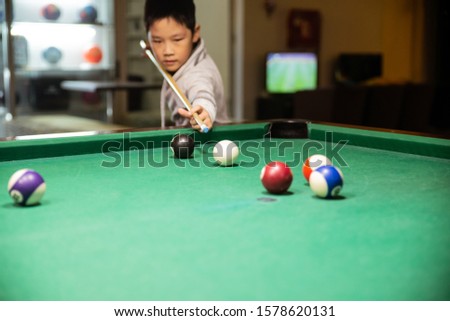 Little Asian boy playing snooker