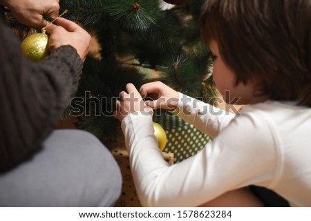 Little boy decorates a Christmas tree for New Year. Happy child wait a Santa under Christmas tree