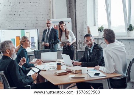 Successful business professionals presenting analytical report while working together with colleagues in the modern office Royalty-Free Stock Photo #1578659503