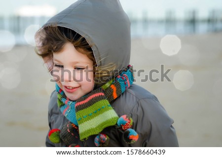 pretty little girl playing on the beach in winter