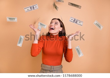 Photo of cheerful cute nice charming attorney earning large salary standing in cash rain wearing red turtleneck isolated over beige pastel color background
