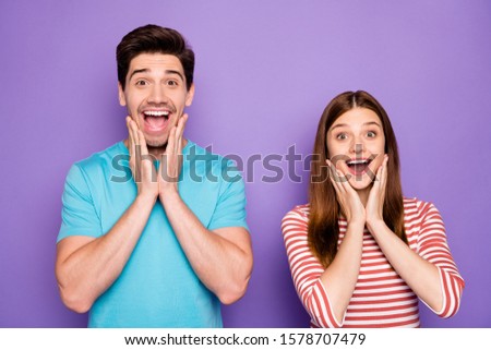 Photo of two funny people couple positive emotions good mood open mouth arms on cheekbones shoppers wear stylish casual outfit t-shirts blue striped isolated purple color background