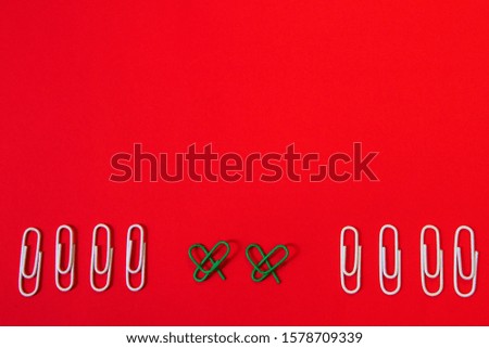 Green paper clips were shaped to heart signs and other paper clips on red background, Christmas day concept.