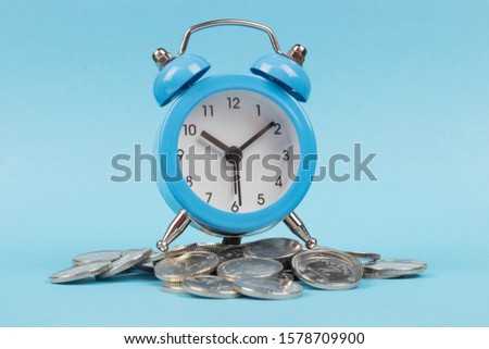 alarm clock on coins, blue background