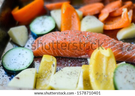 Fresh raw salmon surrounded by fresh vegetables and seasoned with herb and salt before to go in the oven  Royalty-Free Stock Photo #1578710401