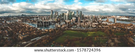London, England - Aerial Panoramic skyline view of Bank and Canary Wharf, central London's leading financial districts with famous skyscrapers at golden hour sunset during cloudy skies.