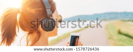Young teenager girl starting jogging and listening to music using smartphone and wireless headphones. Active sport life concept image.
