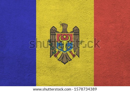 Moldova flag depicted in bright paint colors on old relief plastering wall. Textured banner on rough background