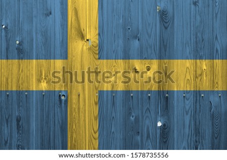 Sweden flag depicted in bright paint colors on old wooden wall. Textured banner on rough background