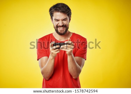 Yellow background mobile phone young man in a red tank top