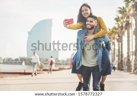 Latin couple taking photos and making videos for social network app in Barcelona - Young people having fun with new technology trends - Travel, tech and millennial concept - Main focus on man face