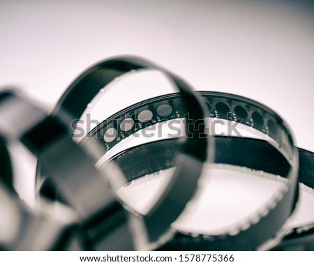old black and white 16mm film wrapped in rings lies on a light background. For your design.