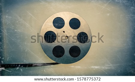 Scratched old black and white 16mm film strip in an aluminum bobbin, blue background. For your design. Web banner.
