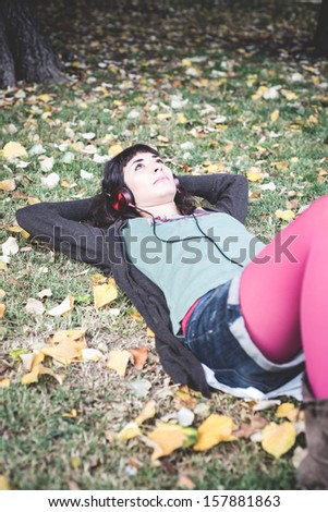 young beautiful woman listening to music at the park in autumn