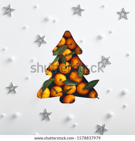 Christmas minimal concept - xmas tree with tangerine and snowflake pattern. Square composition, flat lay, view from above. Winter season. Creative christmas composition.