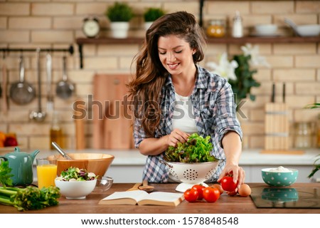 Beautiful young woman is preparing vegetable salad in the kitchen. Healthy Food. Vegan Salad. Diet. Dieting Concept. Healthy Lifestyle. Cooking At Home. Royalty-Free Stock Photo #1578848548