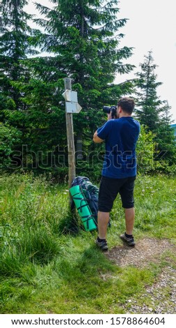 One young man taking photographs direction signwith in highlands. Travelers concept.