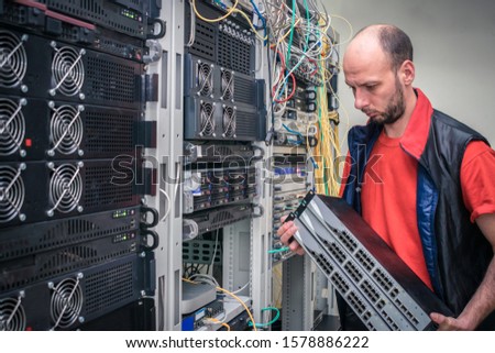 A man installs new switches in the server room. The installer works in a data center. Technology concept. A technician holds in his hands a lot of Internet network equipment.