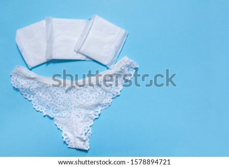 1 female white lace panties, sanitary pads on blue background