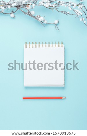 notepad on blue background with Decorated white twigs, holiday concept flat lay. new goals, plans and to do list top view.