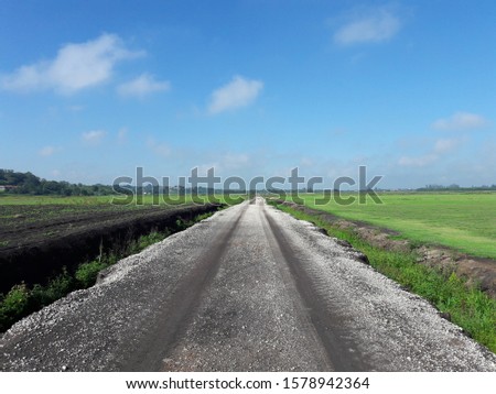 rural landscape with dirt road and blue sky with clouds