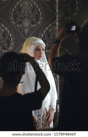 Wedding photographer takes pictures of the bride in make up room. Moslem bride with white gown is being photographed