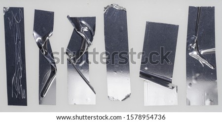 Metallic sticky teared tape shapes cuts isolated on white background. Shiny flexible crumpled glitter holo stickers. Silver shiny metallic stripes, adhesive pieces. Design elements for a poster idea.
