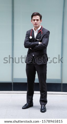  Young handsome medical doctor posing for a camera at outdoor.                              