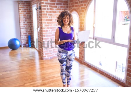 Young beautiful arab sportwoman smiling happy. Standing using laptop before class of yoga at gym