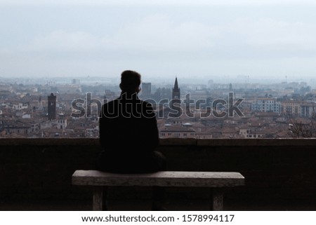 Panoramic view of  Verona, Italy, a silhouette of man sitting on a bench 