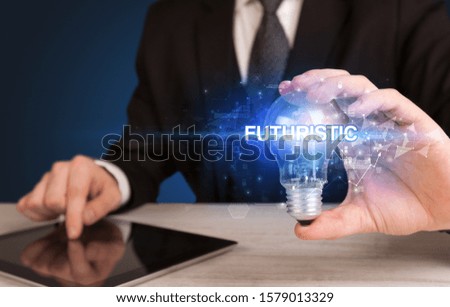 Businessman holding light bulb with FUTURISTIC inscription, innovative technology concept