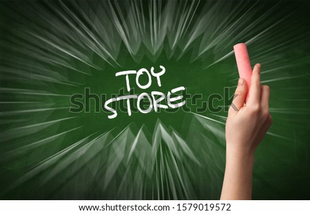 Hand drawing TOY STORE inscription with white chalk on blackboard, online shopping concept