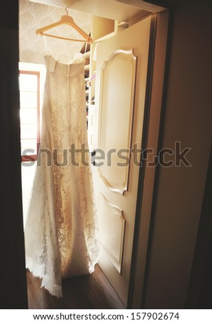 Stylish wedding dress hanging on a door. Bridal morning.