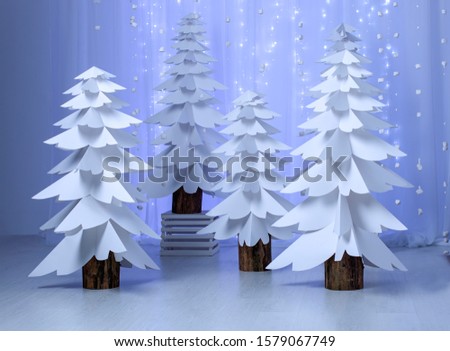 Christmas trees made of paper on blue background. Design decor for the studio.