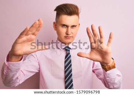 Young handsome businessman wearing shirt and tie standing over isolated pink background doing frame using hands palms and fingers, camera perspective