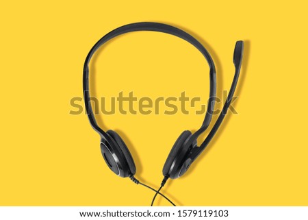 Headphones with a microphone on a yellow background. Top view.