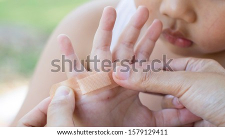 Women are doing the tape wound to the hand of a child. Royalty-Free Stock Photo #1579129411
