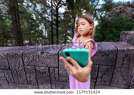 Portrait teenager girl with blond hair doing selfie by phone on beautiful nature background. Stock photography.