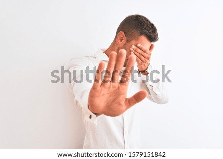 Young handsome business man wearing elegant shirt over isolated background covering eyes with hands and doing stop gesture with sad and fear expression. Embarrassed and negative concept.