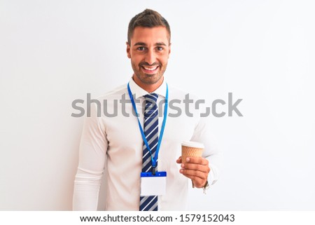 Young handsome business man wearing id pass and drinking coffee over isolated background with a happy face standing and smiling with a confident smile showing teeth