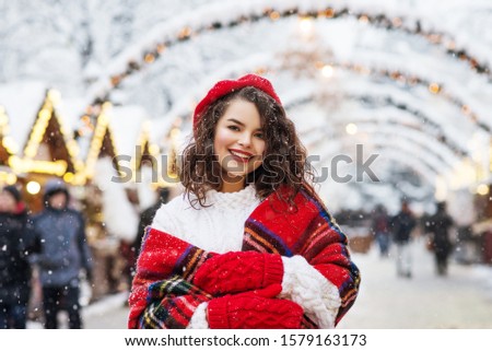Festive Christmas fair: Happy smiling woman posing at decorated street market. Model wearing stylish winter clothes, accessories. Copy, empty space for text