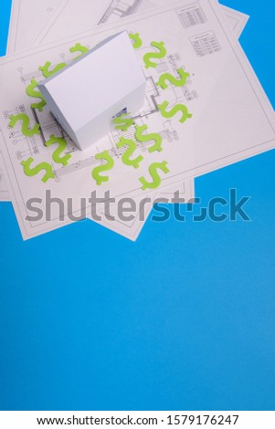 Paper skyscrapers , us dollar money, house projects plan and blueprints on blue background paper. Minimalistic and simple concept, style. Horizontal orientation. View from above. Copy space.