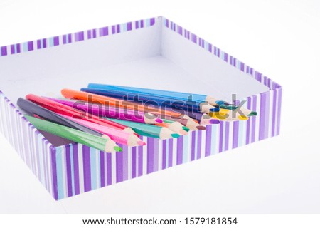 bright multi-colored pencils in a striped box. kids art