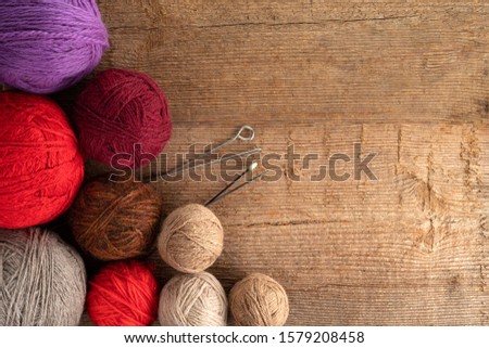 Balls of yarn in different colors with knitting needles on a background of rough wood texture