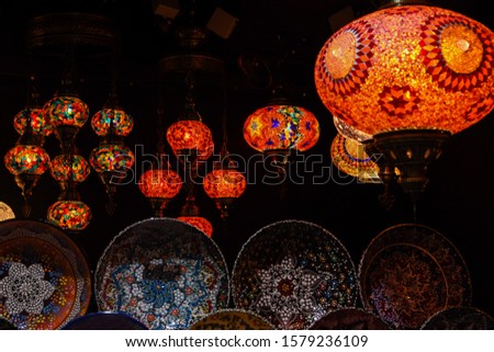 Beautiful paper lanterns in shape of stars as Christmas decorative elements lightning on black background. Bright colorful festive stars hanging at a Christmas Market. New year and Christmas concept.