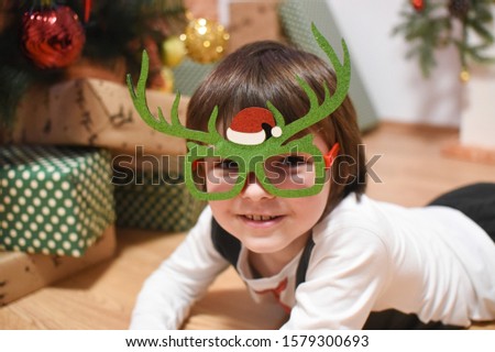 Portrait of happy boy decorating Christmas tree. Child wait a New Year under Christmas tree