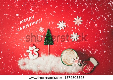Christmas greeting card. Red Christmas background with snow, candy, cute gingerbread cookies and cup of cappuccino