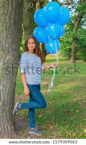 happy young girl with helium balloons in the park