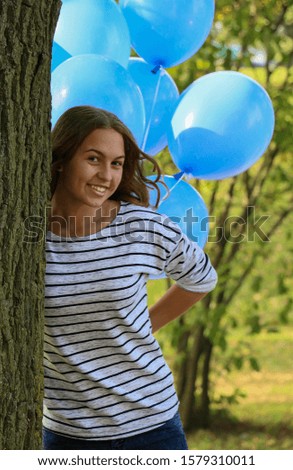 happy young girl with helium balloons in the park on a walk