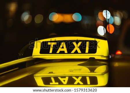 Taxi sign on cab illuminated in dark illuminated street in downtown munich. City bokeh during the night. Rich color